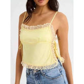 Model displaying a short lace trim satin cami top with an open back.